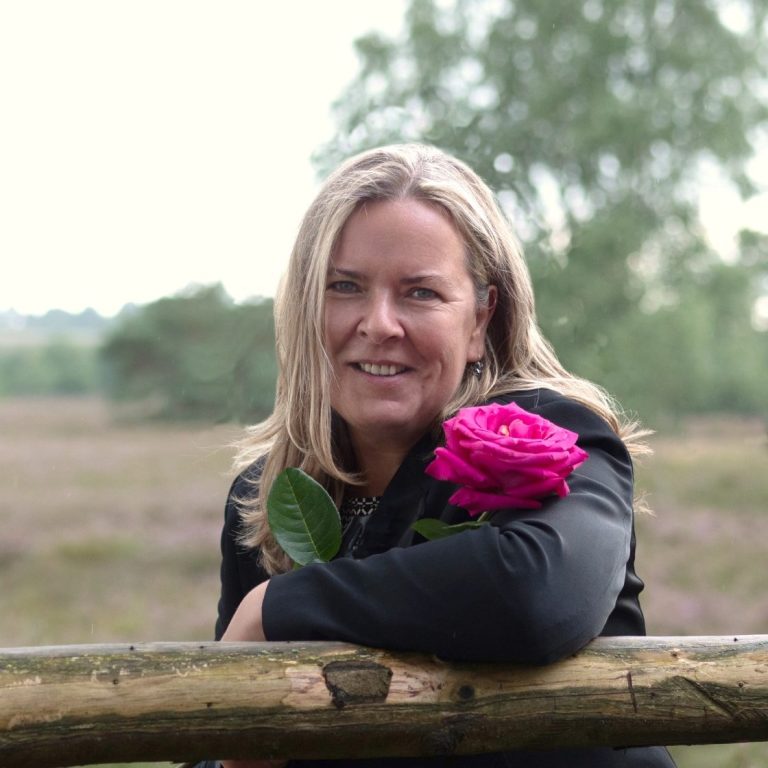 Claudia Rosenberger in der Natur. Mit Wind in den Haaren und einer wunderschönen Rose in der Hand.